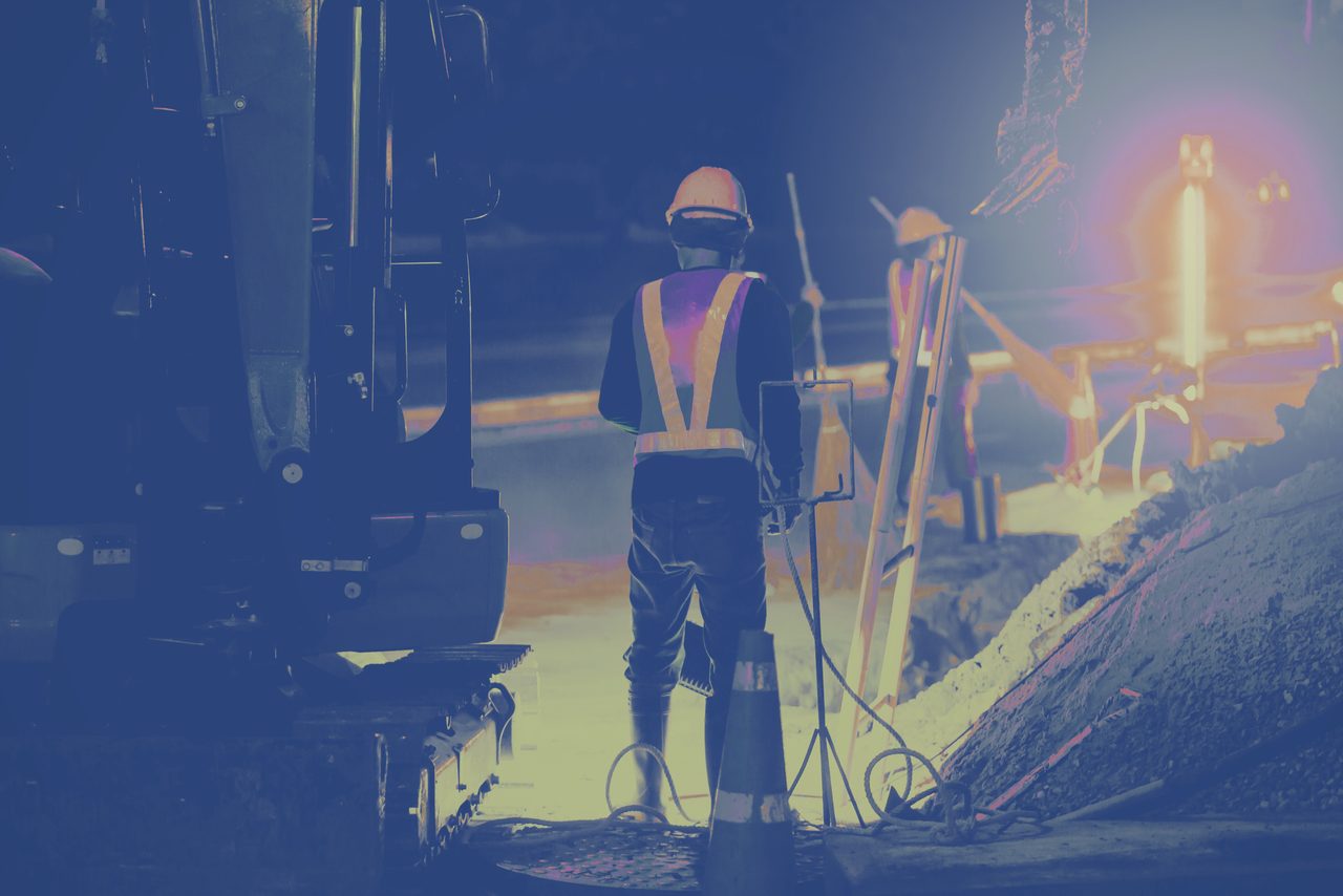 HSE professional in hi-vis overseeing night works under floodlight